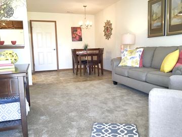 Huber Heights apartment for rent - A living room with a grey couch and a dining table with chairs.