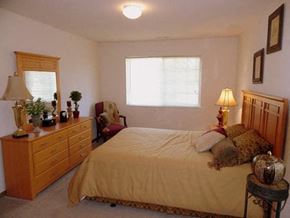 Newark apartment for rent - A bedroom with a bed, nightstand, and a dresser with a lamp on top.