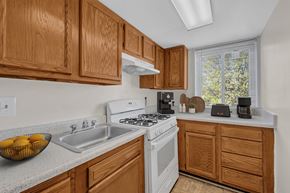 Washington apartment for rent - A kitchen with wooden cabinets and a white stove top oven.