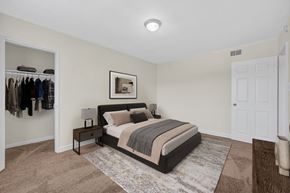 Washington apartment for rent - A bedroom with a large bed and a closet with clothes hanging.