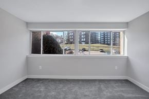 Washington apartment for rent - A room with a large window overlooking a parking lot and buildings.