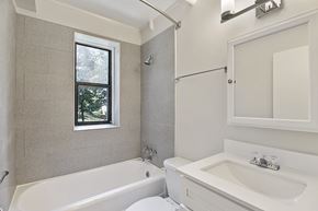 Greenbelt apartment for rent - A white bathroom with a tub, sink, and window.