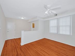 Washington apartment for rent - A room with a ceiling fan and wooden floors.