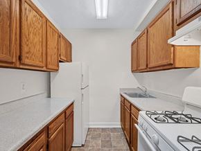 Washington apartment for rent - A kitchen with white appliances and wooden cabinets.