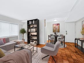 Washington apartment for rent - A living room with a grey couch, a glass coffee table, and a bookshelf.