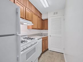 Washington apartment for rent - A kitchen with a white refrigerator, white stove, and brown cabinets.