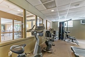 Miami apartment for rent - a gym with exercise machines and chairs in the lobby of a building