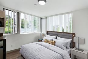 Seattle apartment for rent - A bedroom with a large bed and a window with blinds.