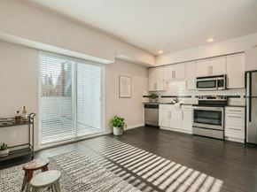Seattle apartment for rent - Open living area with a crisp white kitchen, stainless steel appliances, and hardwood floors at 306 QA in Seattle.