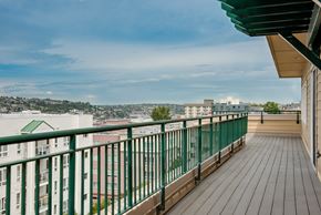 Seattle apartment for rent - A balcony with a green railing overlooks a cityscape.