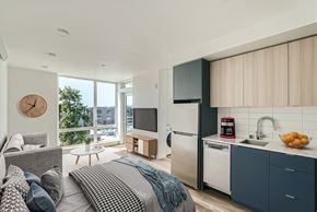 Seattle apartment for rent - A spacious bedroom with a comfortable bed and a desk, featuring large windows and modern decor.