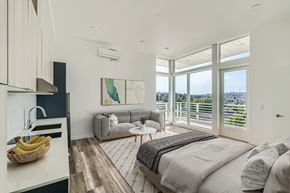 Seattle apartment for rent - A cozy bedroom with a comfortable bed, couch, and large window offering natural light and scenic views.