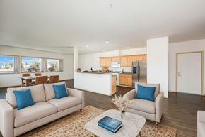 Seattle apartment for rent - A living room with a couch, a coffee table, and a kitchen in the background.
