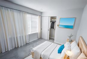 Seattle apartment for rent - A bedroom with a large bed and a painting of a beach scene on the wall.