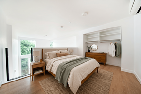Seattle apartment for rent - A bedroom with a large bed and a dresser with clothes hanging on it.