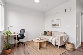 Seattle apartment for rent - Living room with a sofa, jute rug, and a desk and task chair set up as a home office nook.