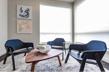 Seattle apartment for rent - a living room with blue chairs and a table and a window