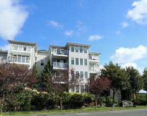 Seattle apartment for rent - A large white apartment building with balconies and multiple windows.