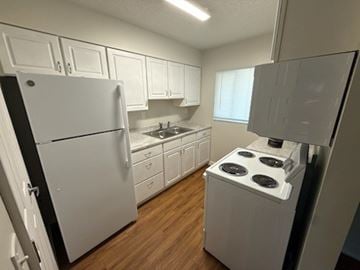 Orange City apartment for rent - A white refrigerator stands in a kitchen with wooden floors and white cabinets.