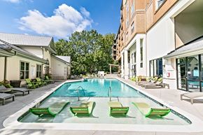 Atlanta apartment for rent - A swimming pool with green lounge chairs and a building in the background.