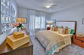 Atlanta apartment for rent - A bedroom with a bed, nightstand, and a vase of flowers.