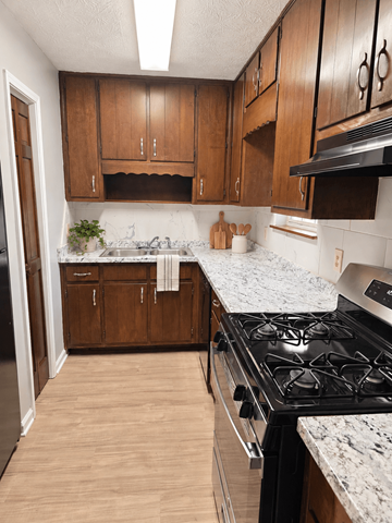 Lawrenceville triplex for rent - A kitchen with wooden cabinets and a black stove top.