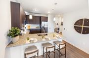 Dacula townhouse for rent - A kitchen with a counter and chairs in the foreground and a dining area in the background.