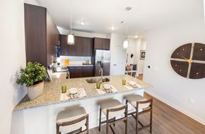 Dacula townhouse for rent - A kitchen with a counter and chairs in the foreground and a dining area in the background.