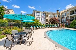 Alpharetta townhouse for rent - A pool area with chairs and umbrellas in front of a building.