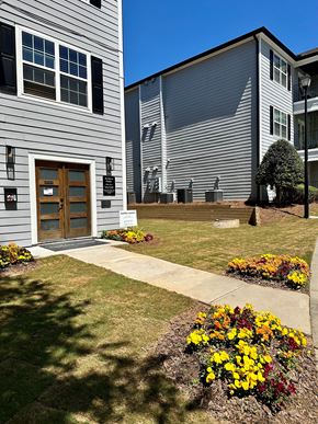 Lilburn apartment for rent - A grey building with a brown door and windows with a sign in front of it.