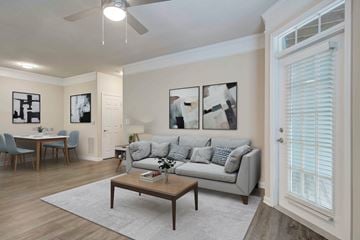 Alpharetta apartment for rent - A living room with a grey couch, a dining table with chairs, a coffee table, and a ceiling fan.