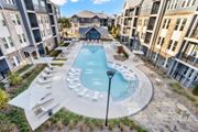 Lawrenceville apartment for rent - A large outdoor swimming pool surrounded by lounge chairs and umbrellas.