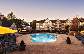 Duluth apartment for rent - A large swimming pool surrounded by lounge chairs and umbrellas in front of a building.