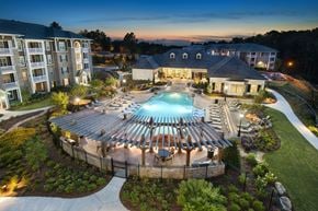 Duluth apartment for rent - A large building with a pool in the middle of a courtyard surrounded by a fence.