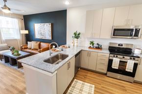 Mcdonough apartment for rent - an open kitchen and living room with a granite counter top at Woodlands Creekside Apartments, McDonough