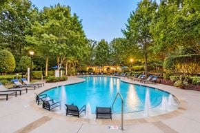 Charlotte apartment for rent - A round swimming pool surrounded by trees and lounge chairs.