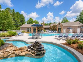 Alpharetta apartment for rent - A large outdoor swimming pool with a rock feature in the middle.