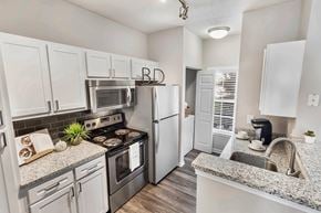 Brentwood apartment for rent - A kitchen with white cabinets and a granite countertop.