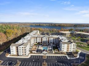 Farmington apartment for rent - A large white building with a pool in the middle of a parking lot.