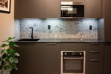 Hartford apartment for rent - A modern kitchen with a dark countertop and a stone backsplash.