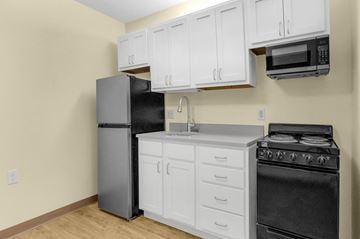 Williamstown apartment for rent - a kitchen with white cabinets and black appliances and a refrigerator