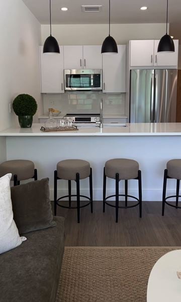 Newtown apartment for rent - A kitchen with white cabinets and a counter with four stools.