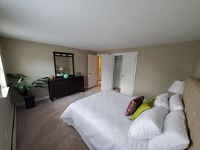 Rocky Hill apartment for rent - a bedroom with a large white bed and a dresser with a mirror at Greenfield Village Apartments, Rocky Hill