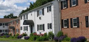 Rocky Hill apartment for rent - a white and brick building with flowers in front of it at Greenfield Village Apartments, Rocky Hill, Connecticut