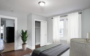 Hartford apartment for rent - A bedroom with a bed, a plant, and a bathtub.