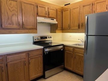 New Haven apartment for rent - A kitchen with wooden cabinets and a stainless steel refrigerator.