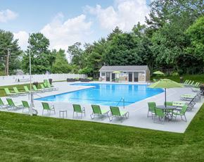 Rocky Hill apartment for rent - a swimming pool with green chairs and umbrellas around it at Greenfield Village Apartments, Rocky Hill