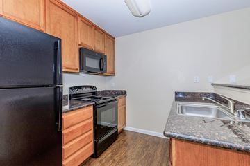 Pittsburg apartment for rent - A kitchen with a black refrigerator, microwave, and stove.
