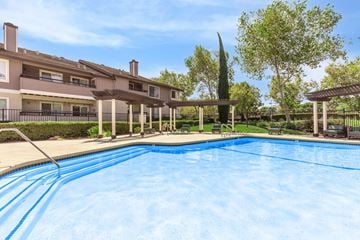 Pittsburg apartment for rent - A swimming pool in front of a building with a tall tree in the background.