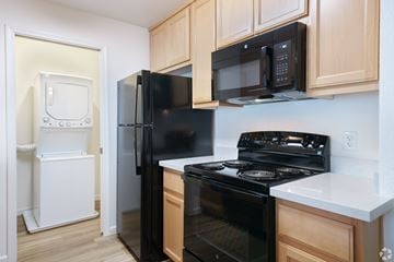 Pittsburg apartment for rent - A black refrigerator and oven in a kitchen with wooden cabinets.